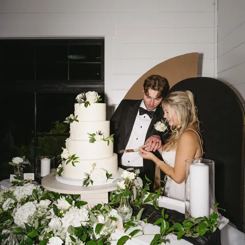 Five-tier white buttercream wedding cake with fresh flowers