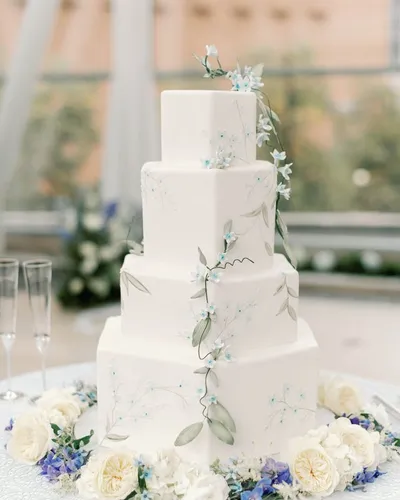 White wedding cake with blue florals at the reception