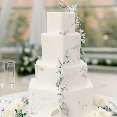 White wedding cake with blue florals at the reception