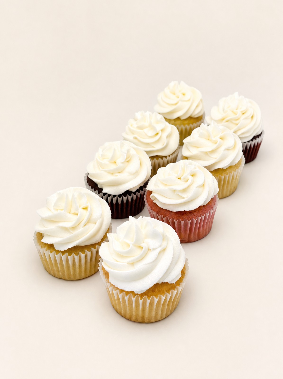 Assorted buttercream cupcakes in colorful wrappers, the kind of mixed dozen Indianapolis cupcake bakeries sell in-store.