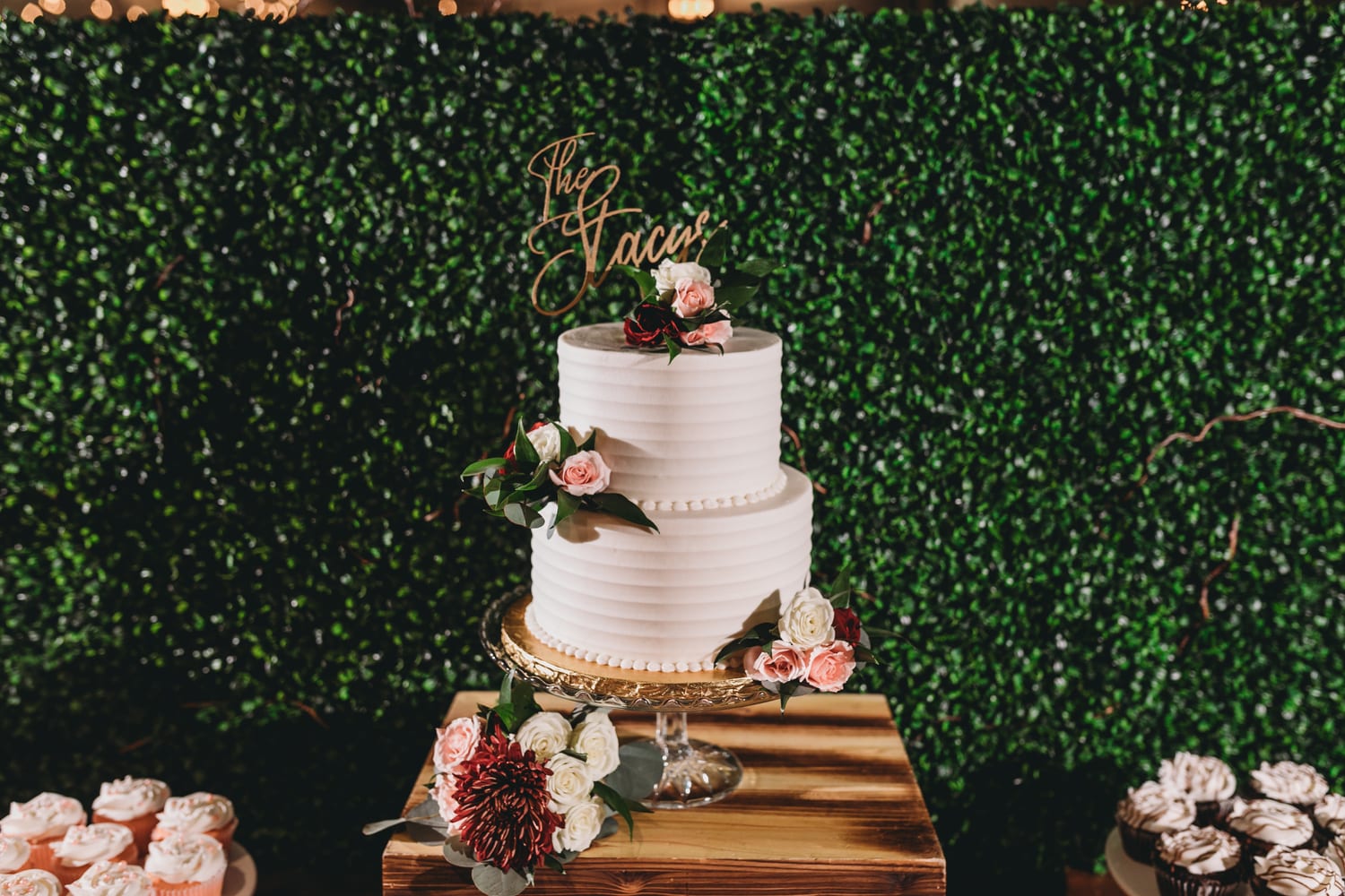 An elegant two-tier white buttercream wedding cake with fresh roses on a gold stand, a custom wedding cake by Sweet Escape Cake Company in Indianapolis.