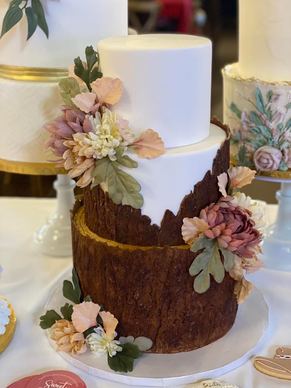 A rustic three-tier wedding cake with tree-bark texture and sage greenery, ideal for a fall or seasonal wedding flavor at Sweet Escape Cake Company in Indianapolis.