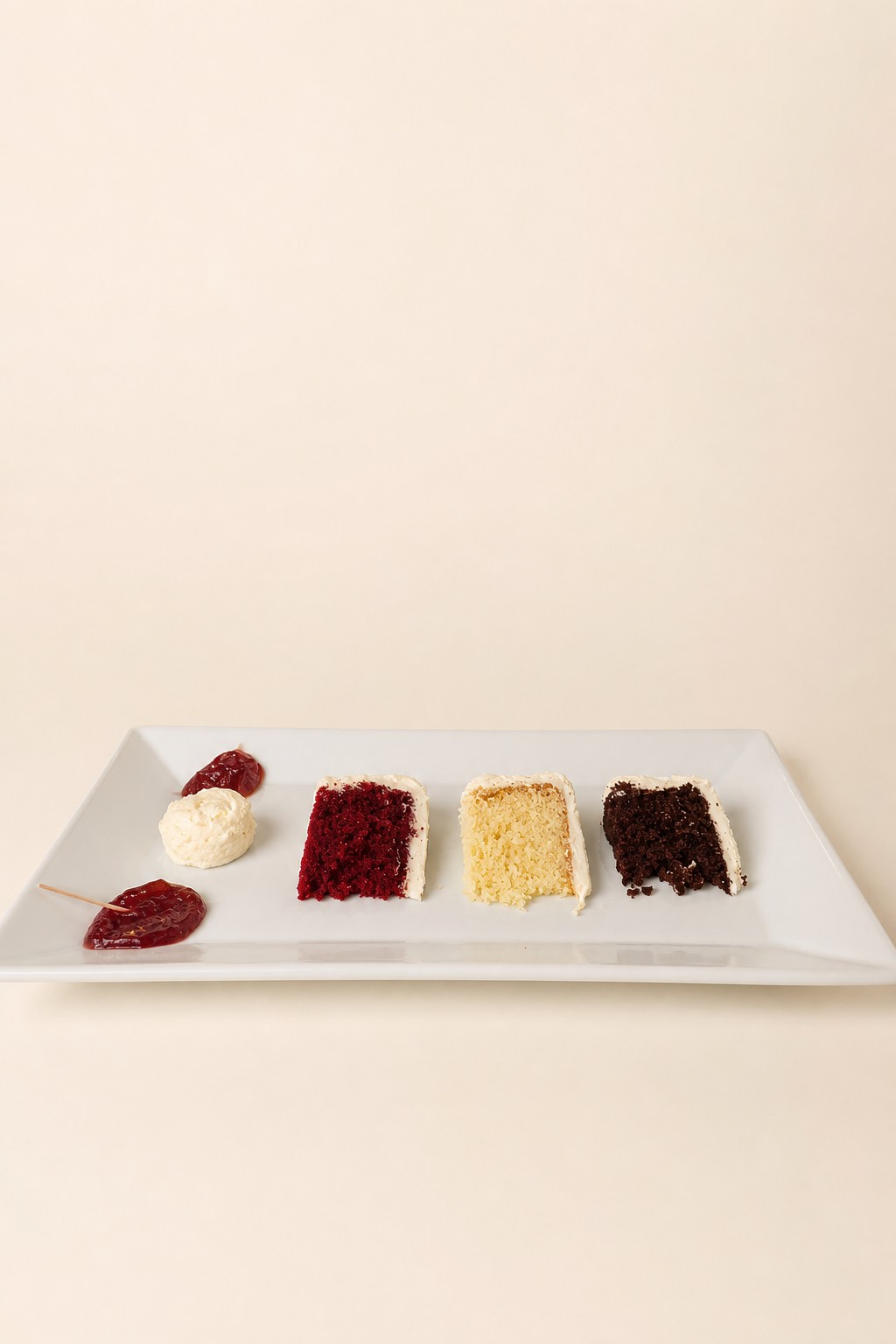 Slices of red velvet, vanilla, and chocolate cake plated with cream and berry jam fillings at a Sweet Escape Cake Company tasting in Indianapolis.