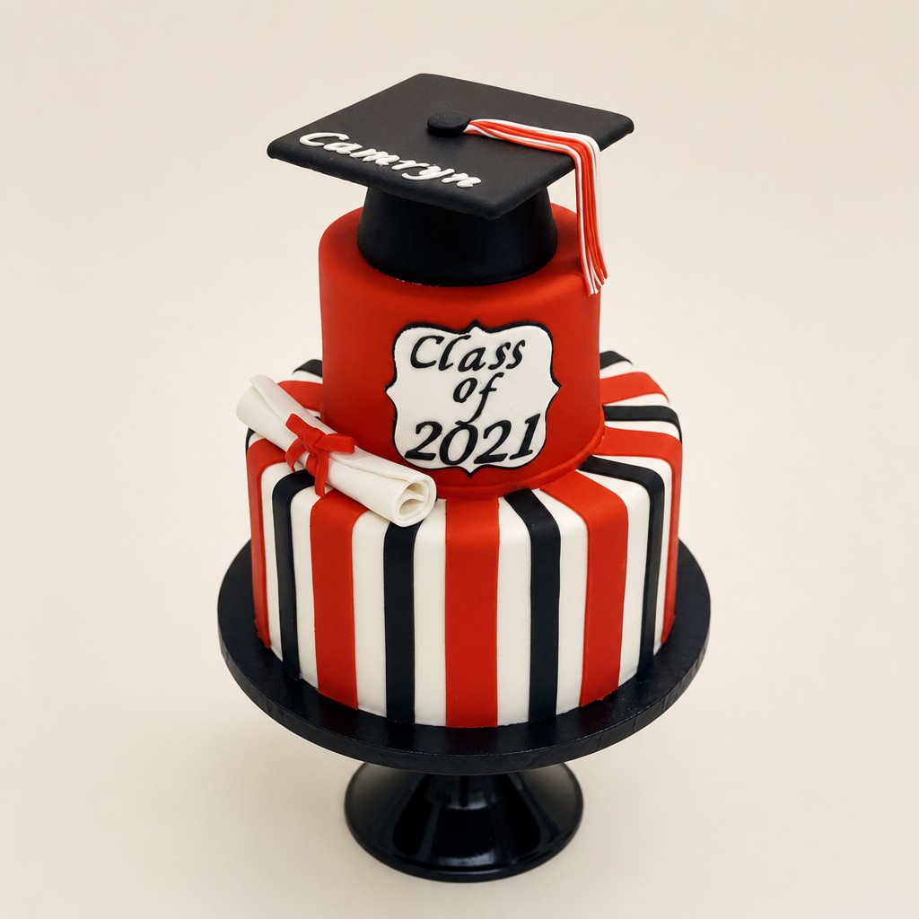 A striped two-tier graduation cake with a black fondant graduation cap and rolled diploma made by an Indianapolis bakery.