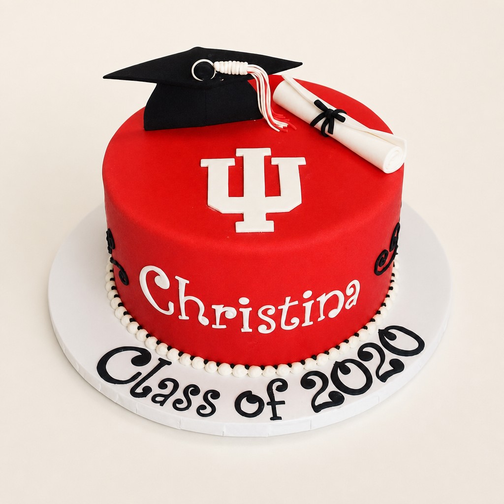 A red single-tier high school graduation cake with a black fondant graduation cap, tassel, and diploma scroll from an Indianapolis bakery.