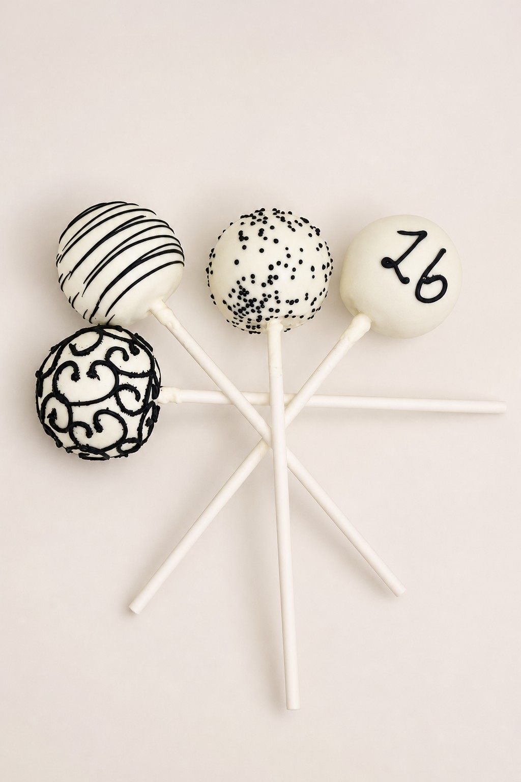 Black and white cake pops with stripes, dots, swirls and a piped number, a gothic Halloween party favor idea from an Indianapolis bakery.