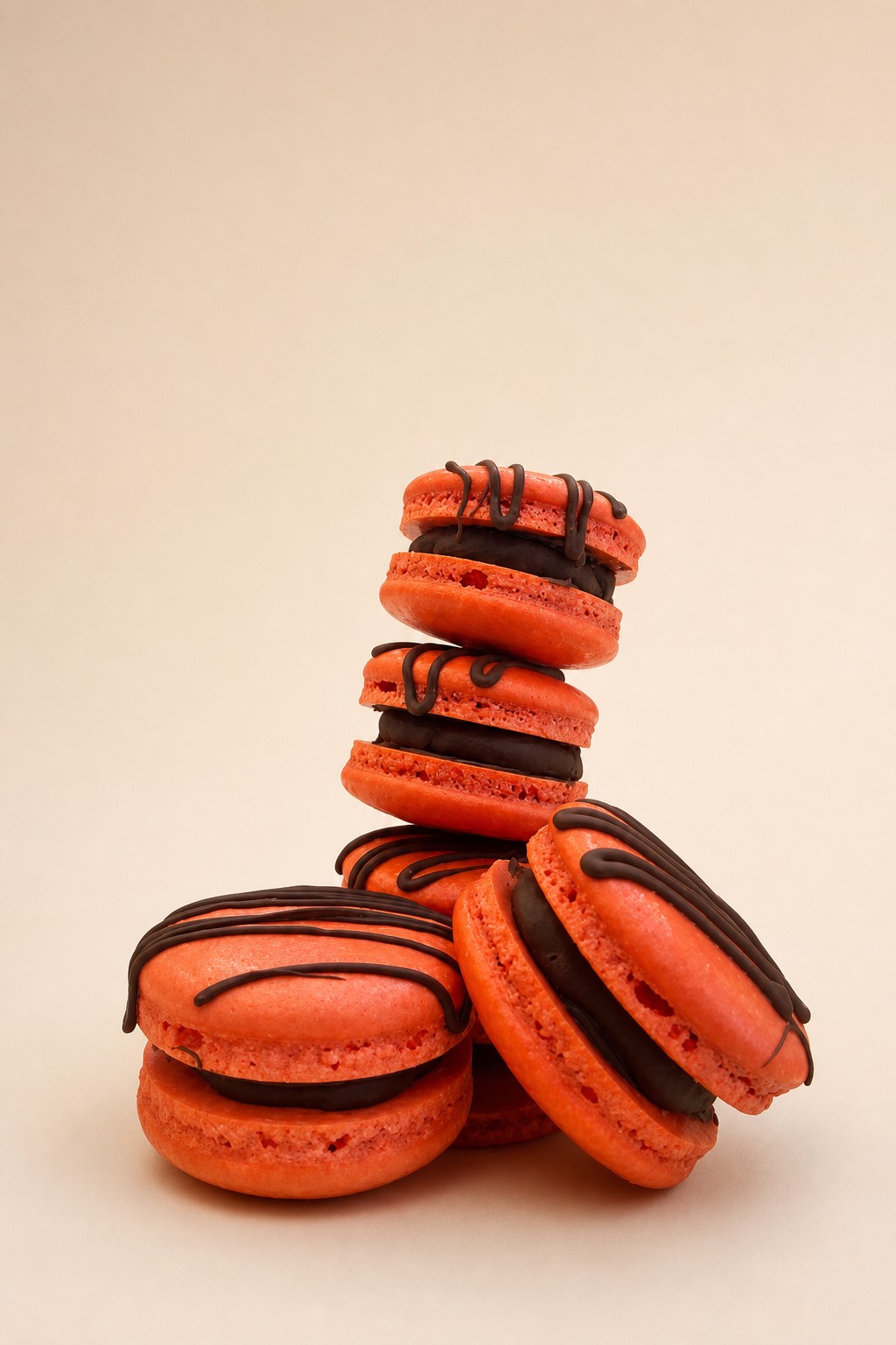 A stack of orange macarons with dark chocolate drizzle, an adult Halloween dessert table idea from an Indianapolis bakery.