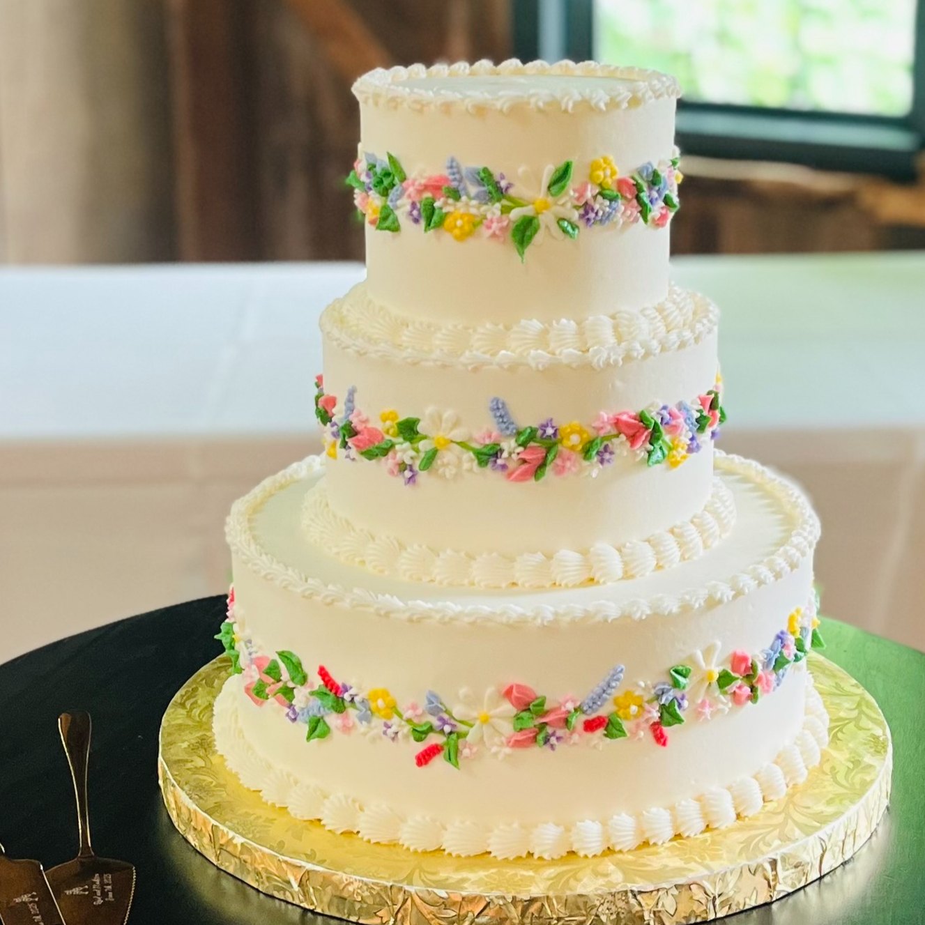 A three-tier white buttercream wedding cake with colorful hand-piped floral garlands by Sweet Escape Cake Company in Indianapolis.
