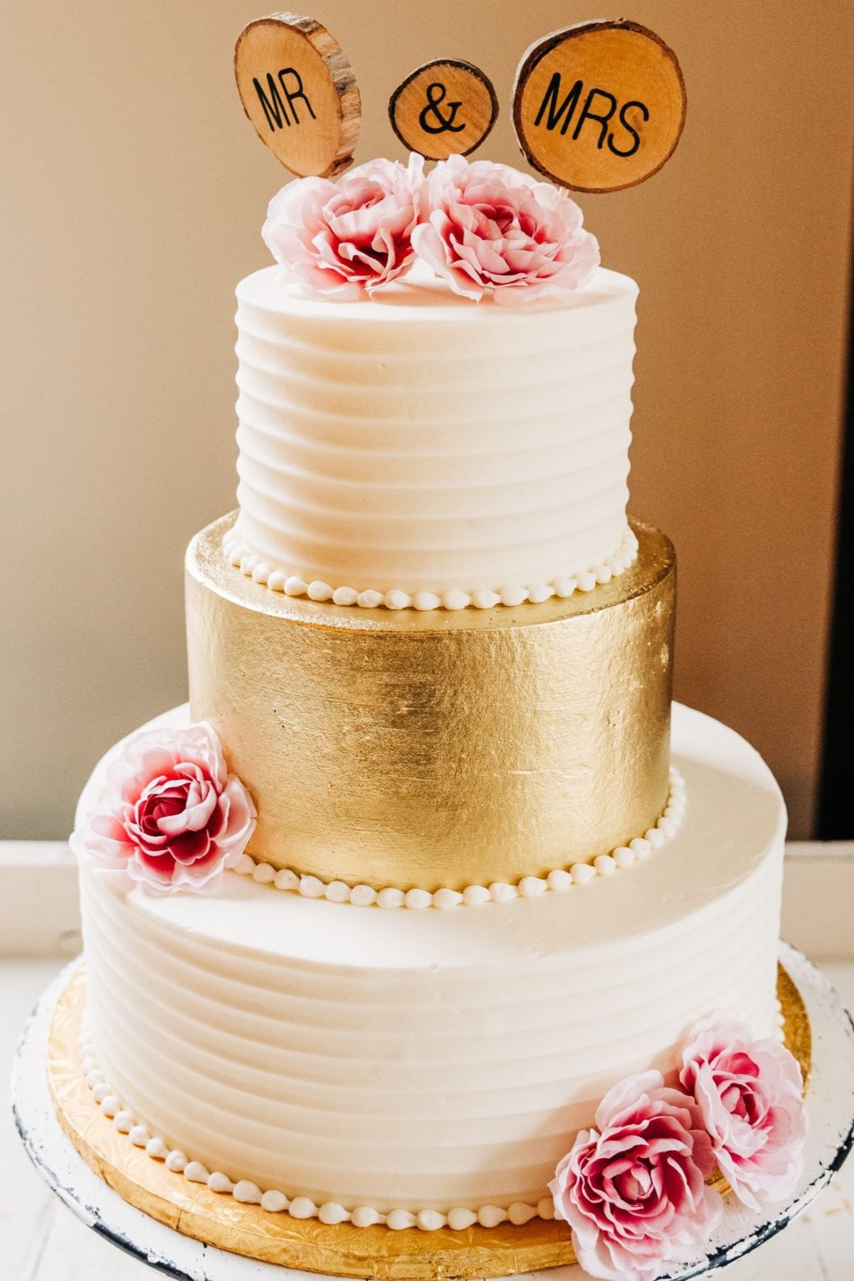 An elegant tiered buttercream wedding cake with blush and gold details by Sweet Escape Cake Company.