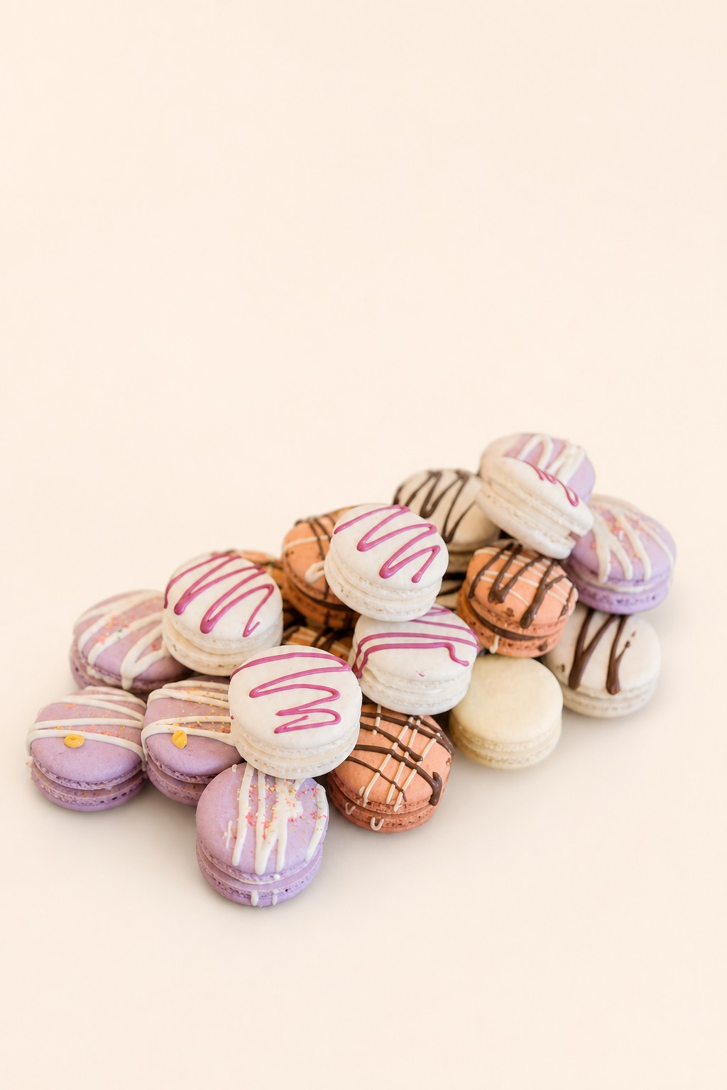 A wooden tray of pastel mini macarons in lavender, pink, and cream, styled for a shower dessert table by Sweet Escape Cake Company.