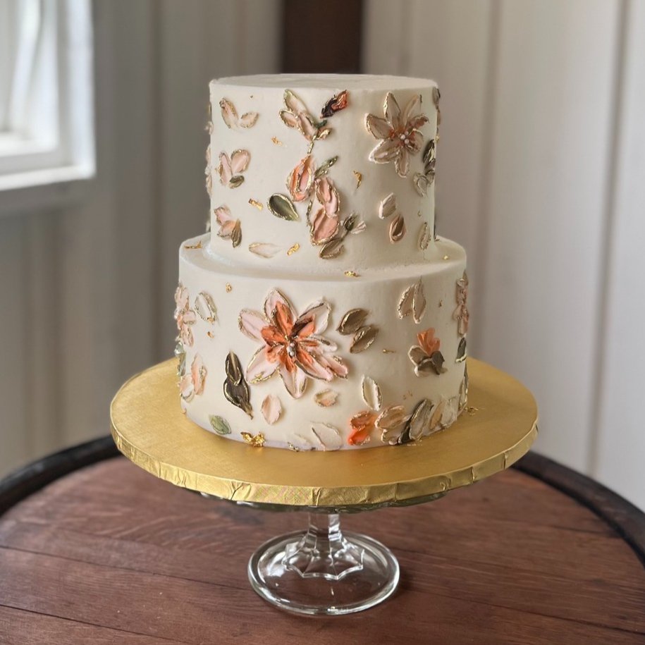 A two-tier cream buttercream wedding cake with textured floral detail and gold leaf, an Indianapolis wedding cake by Sweet Escape.