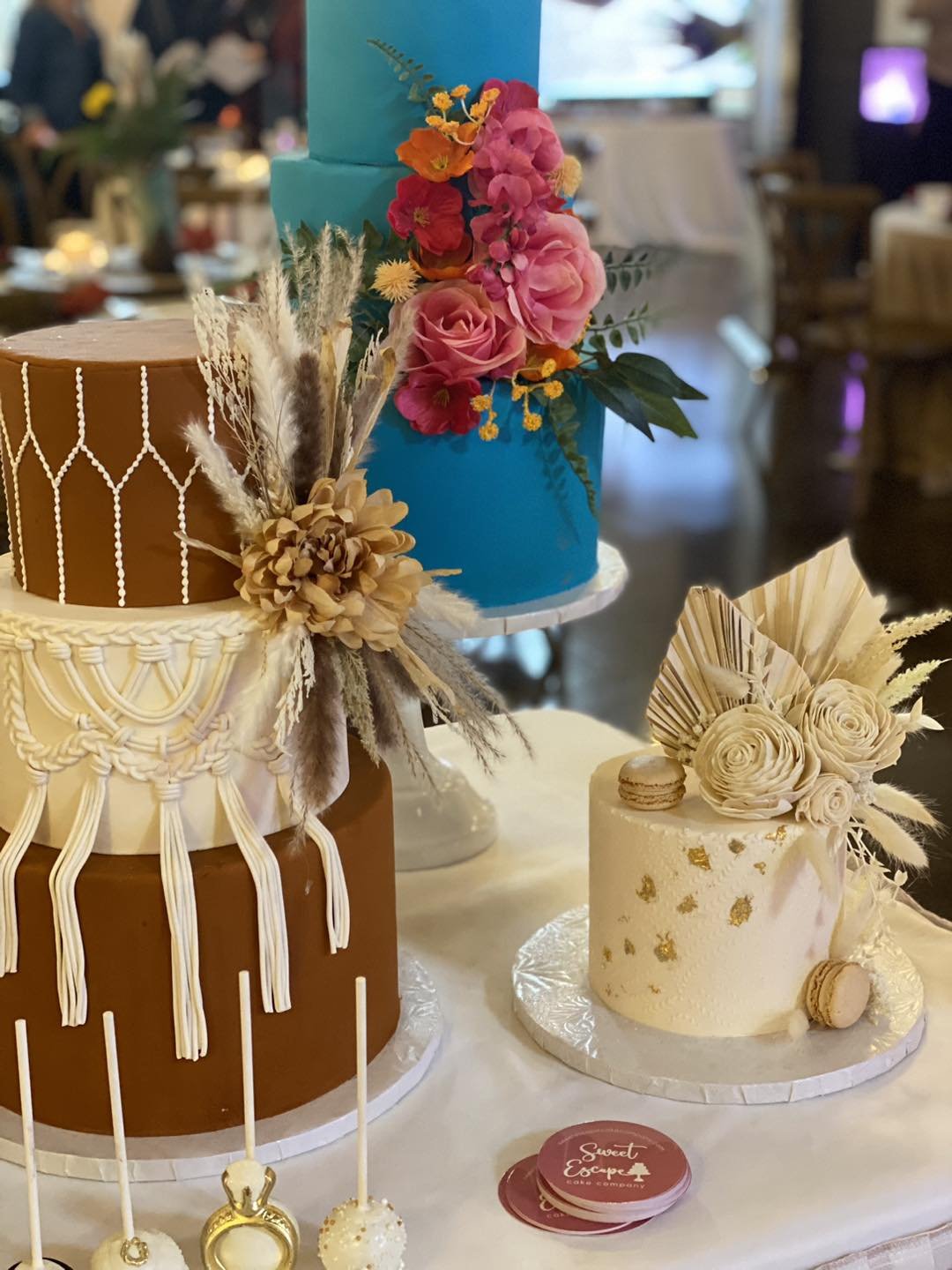 A rustic boho wedding cake dessert bar with macrame buttercream piping, pampas grass, and a bold blue floral cake by Sweet Escape Cake Company in Indianapolis.