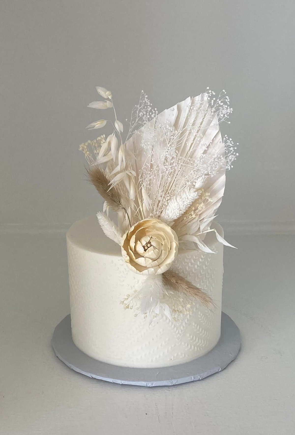 A single-tier round textured buttercream wedding cake topped with dried flowers, a 2026 wedding cake design by Sweet Escape Cake Company in Indianapolis.