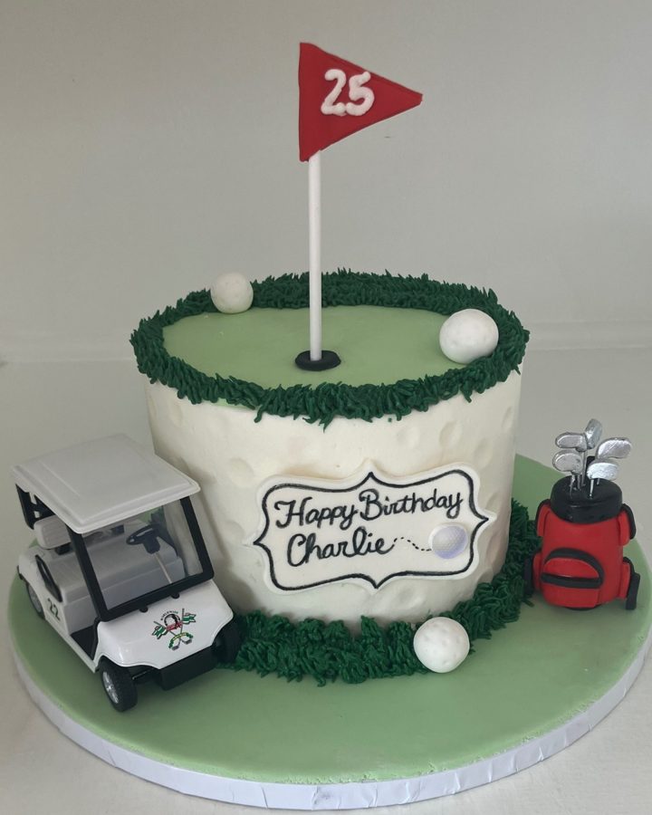 A round, single-tier golf-themed birthday cake featuring a white buttercream base, a green golf course top with a flag displaying the number
