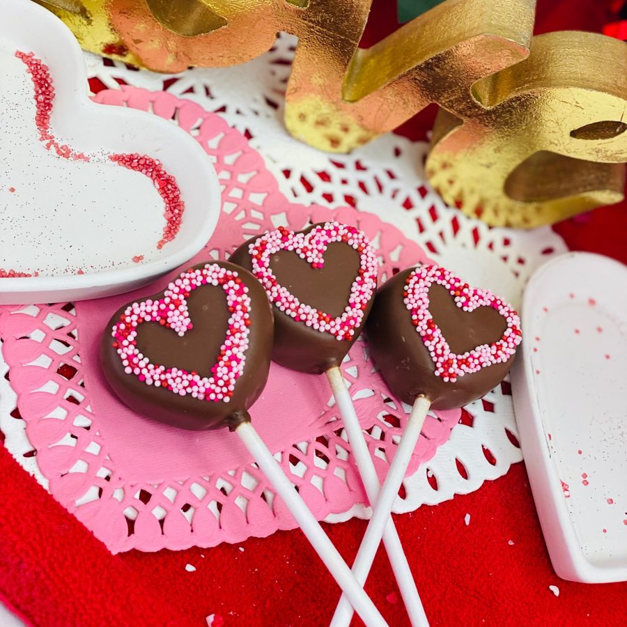 Heart-shaped chocolate cake pops decorated with pink and red sprinkles, ideal for Valentine's Day celebrations.