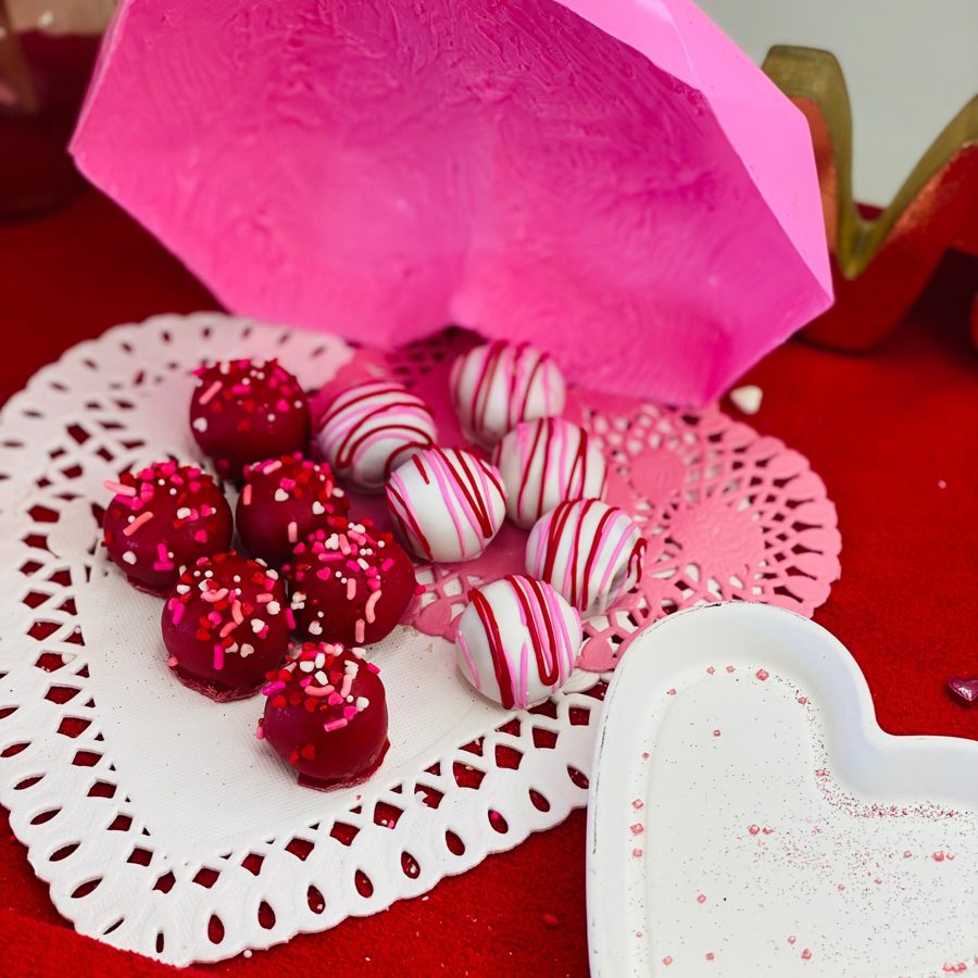 Festive red cake pops with colorful sprinkles and white cake pops with pink and red drizzles, displayed on doilies, ideal for Valentine's Da