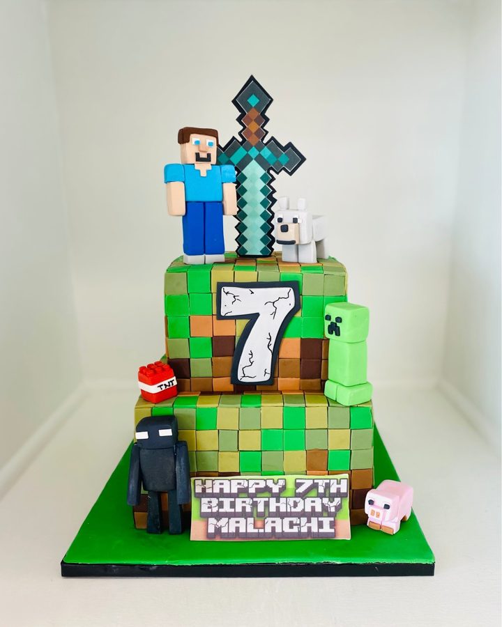 A two-tier square Minecraft-themed birthday cake for Malachi, featuring fondant blocks, pixelated characters like Steve, Creeper, Enderman, 