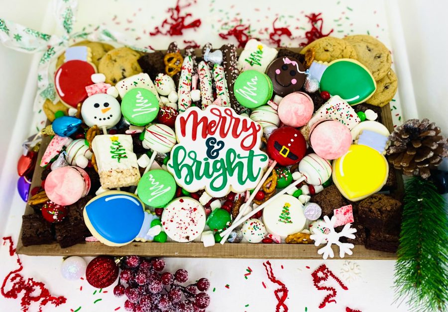 A vibrant Christmas holiday dessert bar featuring an assortment of festive decorated cookies, colorful macarons, chocolate-dipped pretzels, 