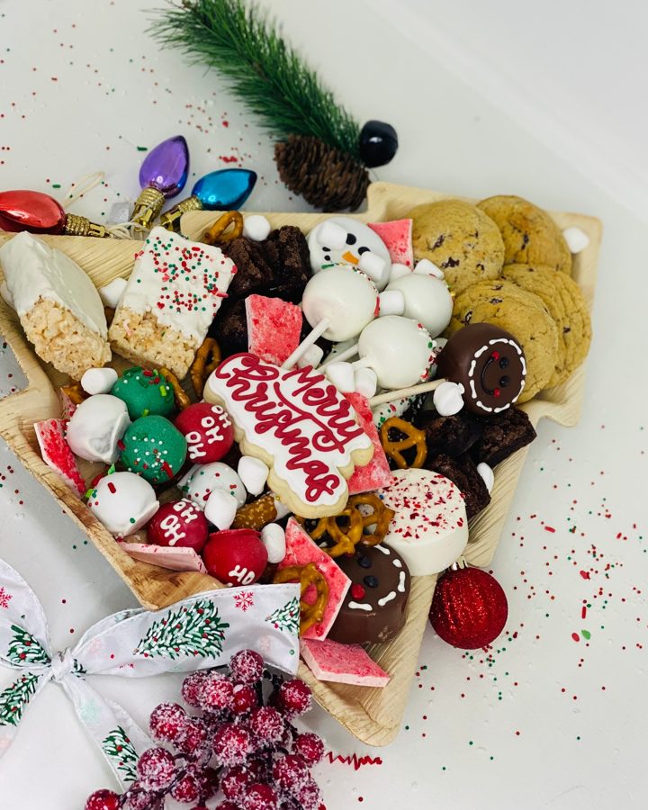 A festive Christmas dessert platter filled with an assortment of holiday treats, including decorated cookies, cake pops, chocolate-dipped it