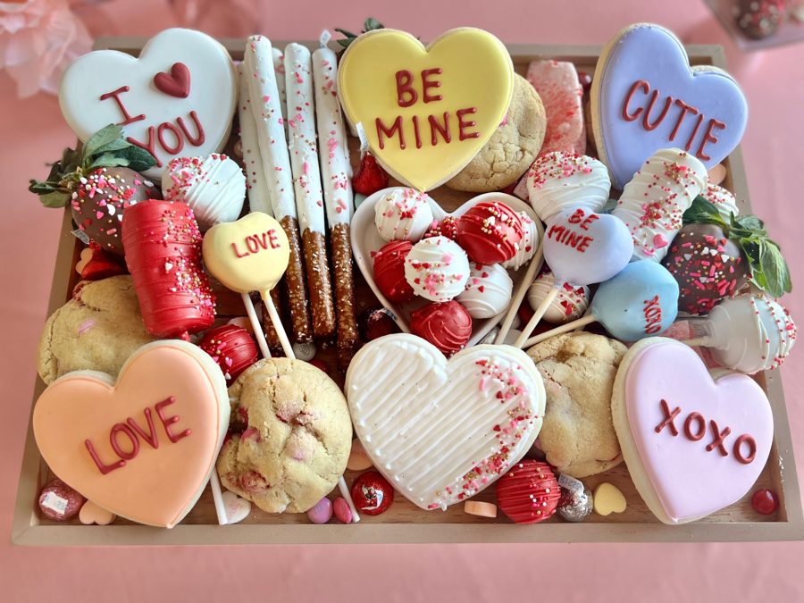 A festive Valentine's Day dessert platter featuring an assortment of heart-shaped sugar cookies with royal icing messages like 'I heart YOU'