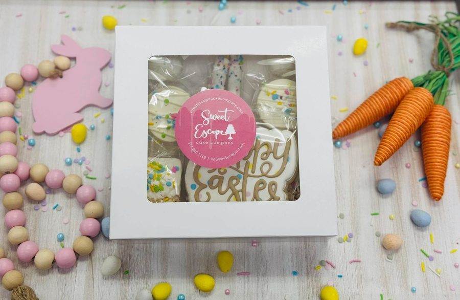 A white window box filled with assorted Easter-themed treats, including royal icing decorated cookies and sprinkle-covered desserts from Swe