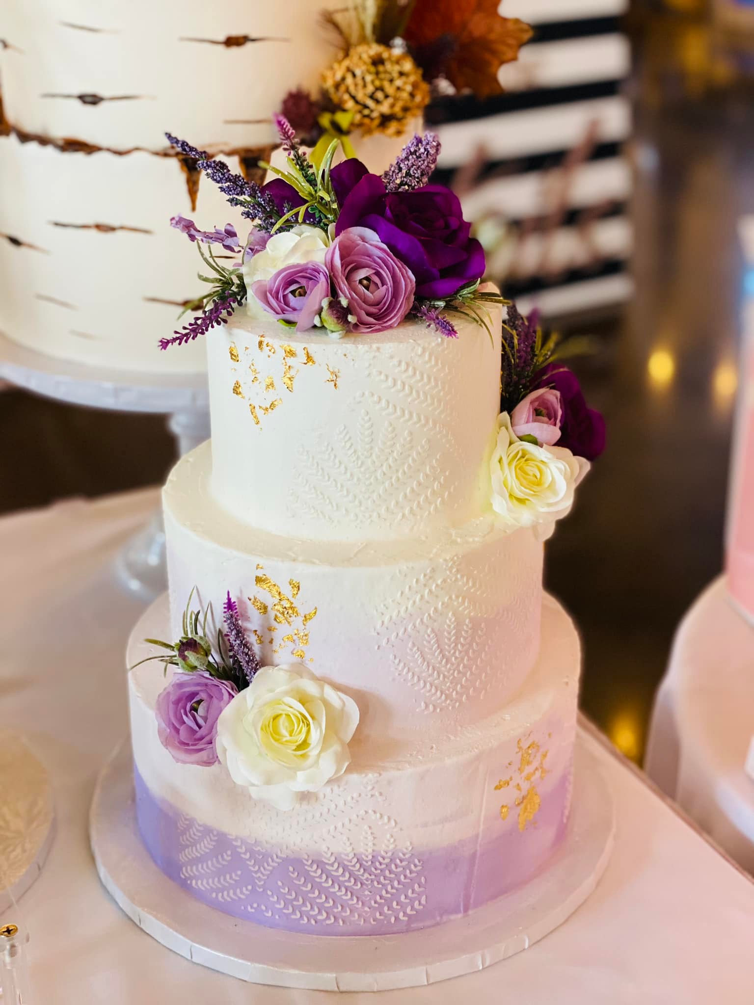 Three-tier white wedding cake with blush and burgundy florals