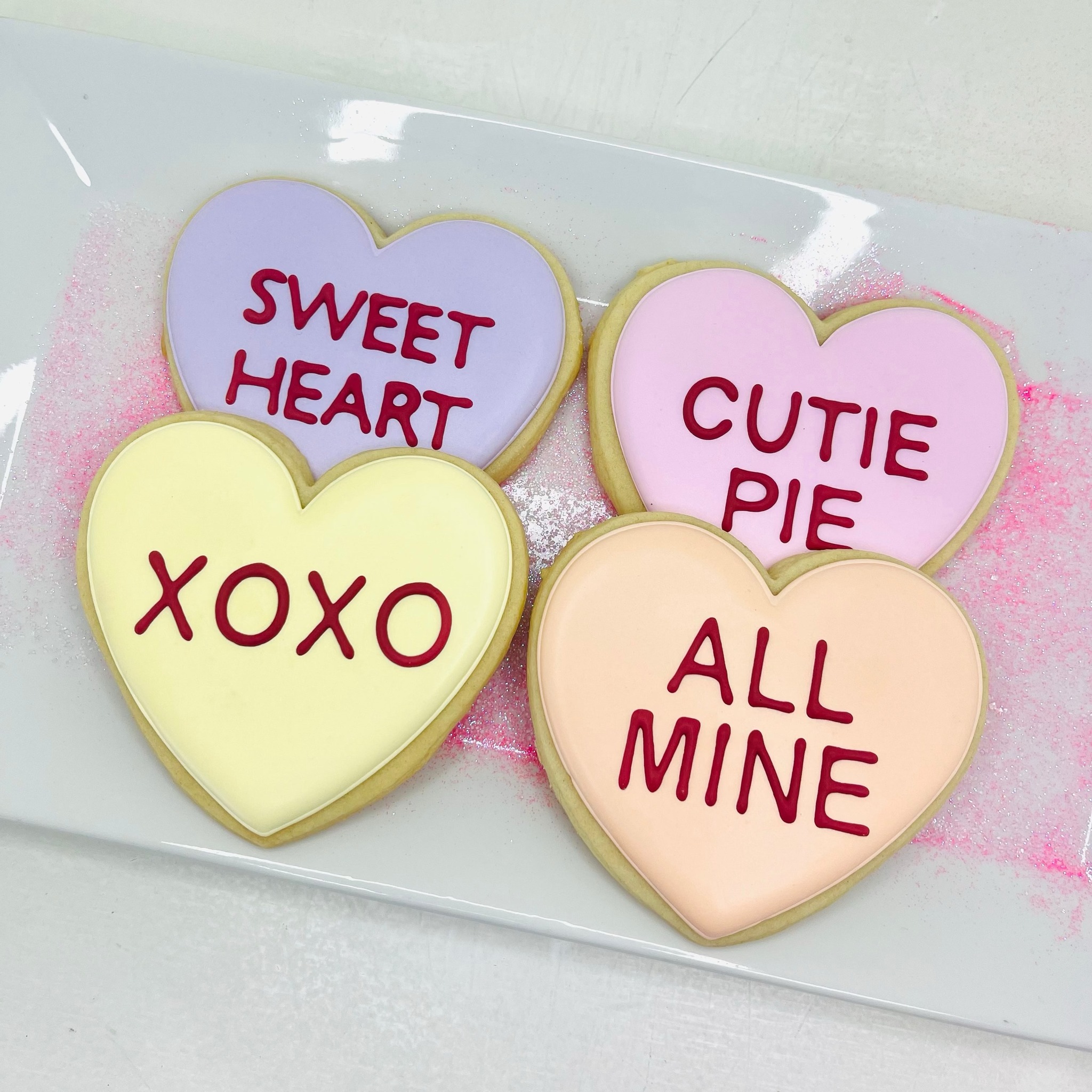 Pastel conversation-heart sugar cookies reading sweet heart, cutie pie, xoxo, and all mine